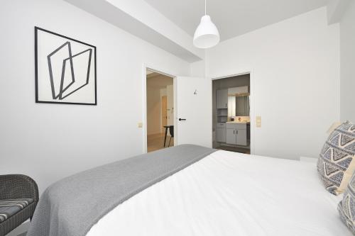 a white bedroom with a bed and a couch at House 22 in Kortrijk
