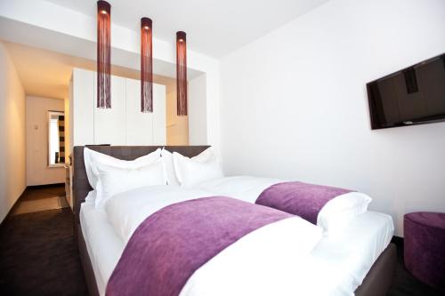 a bedroom with a large bed with white sheets and purple blankets at Goodman's Living in Berlin
