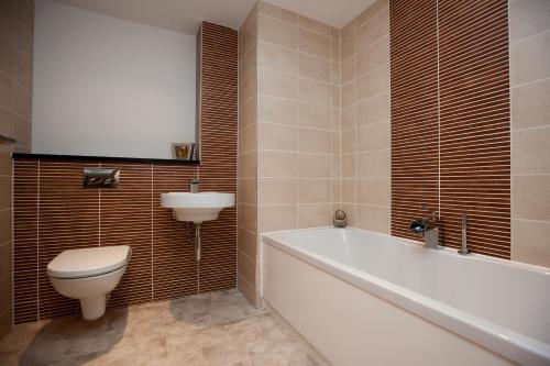 a bathroom with a toilet and a tub and a sink at The Spires Serviced Apartments Glasgow in Glasgow