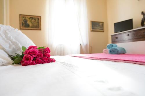 MassaにあるLa Querciolaia B&Bの白いベッドに座る赤いバラの花束