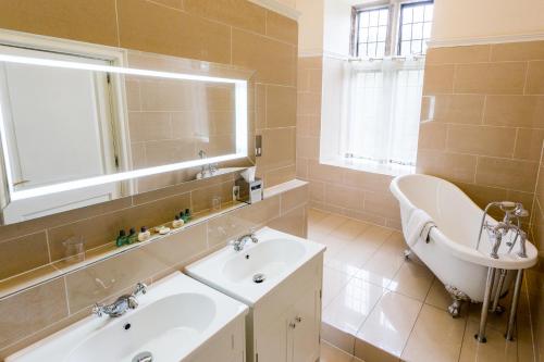 a bathroom with a tub and a sink and a tub at Hellaby Hall Hotel; BW Signature Collection in Hellaby
