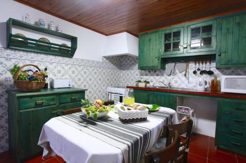 kuchnia z zielonymi szafkami i stołem z jedzeniem w obiekcie Casa da Roseira w mieście Nordeste
