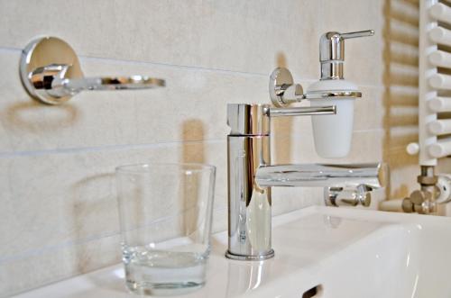 a sink with a drinking glass next to a faucet at Chalet Rivendell - GRIWA RENT AG in Grindelwald