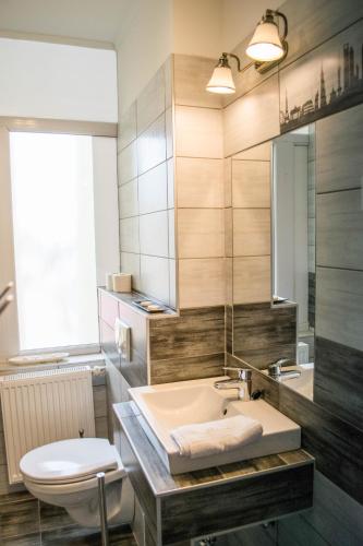 a bathroom with a sink and a toilet and a mirror at Petra Hotel in Nyíregyháza