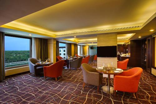 a restaurant with tables and chairs and a large window at Novotel Hyderabad Airport in Hyderabad