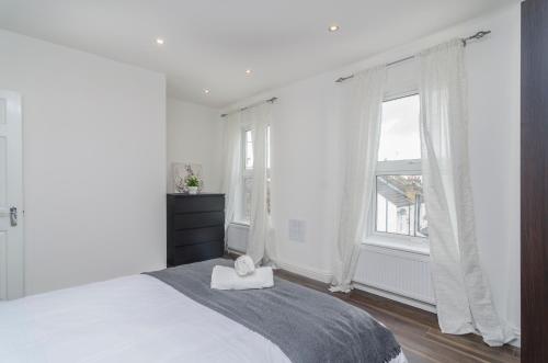 a white bedroom with a bed and a window at Alabama Place in Plumstead