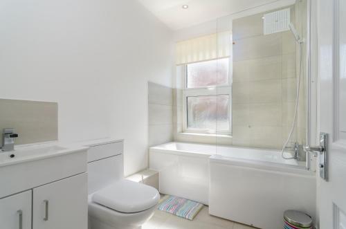a white bathroom with a toilet and a sink at Alabama Place in Plumstead