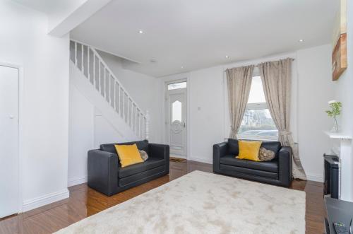 a living room with two black chairs and a rug at Alabama Place in Plumstead
