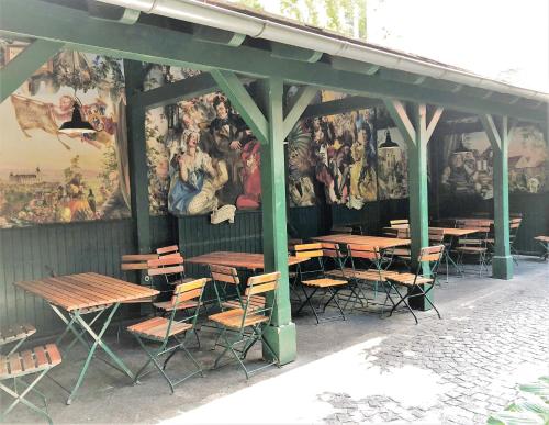 a group of tables and chairs in front of a wall with paintings at Best Place Apartments Vienna in Vienna