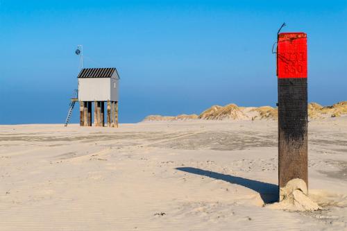 a wooden pole in the middle of a beach with a lighthouse at Hotel De Walvisvaarder in Lies