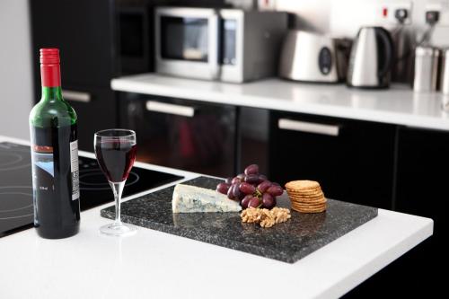 a bottle of wine and a glass of wine and grapes at The Spires Serviced Apartments Glasgow in Glasgow