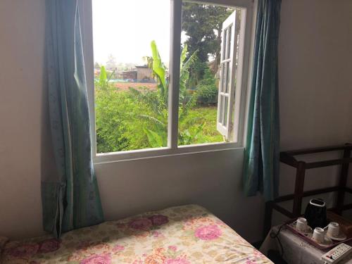 a bedroom with a window and a bed with a floweridered blanket at Pedro View Homestay in Nuwara Eliya