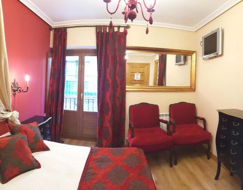 Schlafzimmer mit roten Stühlen, einem Bett und einem Spiegel in der Unterkunft Legado de Ugarte, Casa Rural in Laguardia