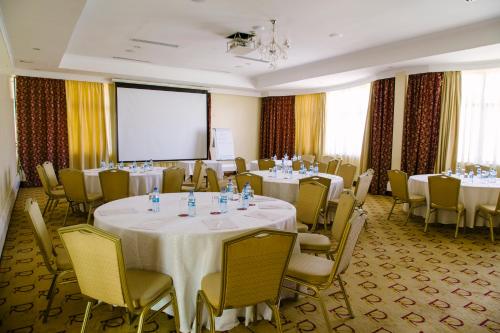 a conference room with tables and chairs and a projection screen at Boma Inn Nairobi in Nairobi
