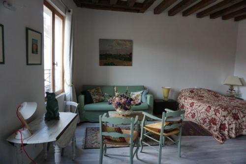 ein Wohnzimmer mit einem Bett, einem Tisch und Stühlen in der Unterkunft Rémalard appartement in Rémalard