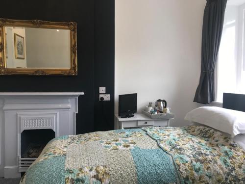 a bedroom with a bed and a mirror and a fireplace at The Nags Head - Room only accommodation in Lyme Regis