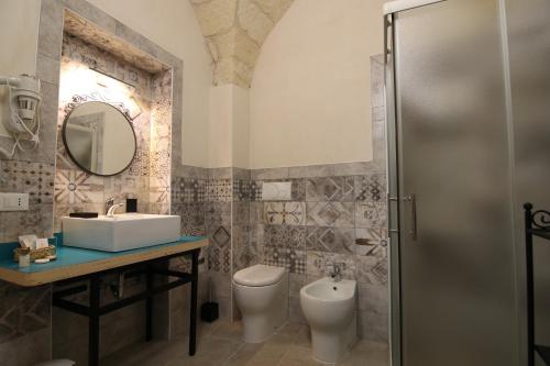 a bathroom with a sink and a toilet and a mirror at Corte Manzoni in Melendugno