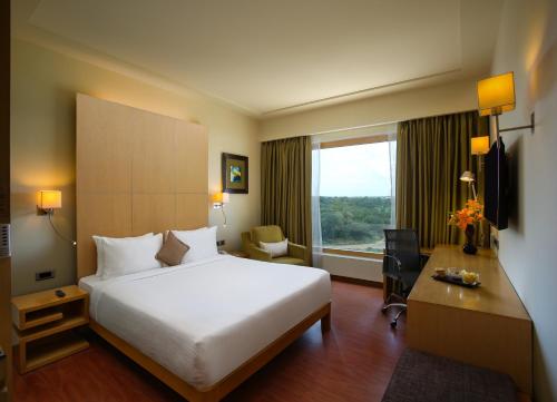 a hotel room with a bed and a desk and a window at Novotel Hyderabad Airport in Hyderabad