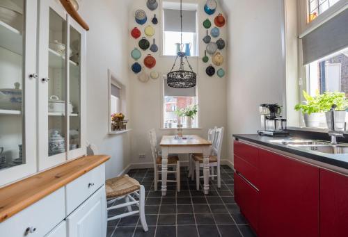 a kitchen with a table and a kitchen with red cabinets at Vakantiehuis Stadszicht in Ootmarsum
