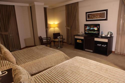 a hotel room with two beds and a flat screen tv at Akkoc Boutique Hotel in Adana