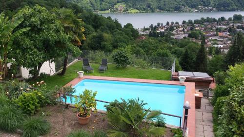 a swimming pool in a garden with a view of a lake at Appartamenti Villa Colibri in Neggio