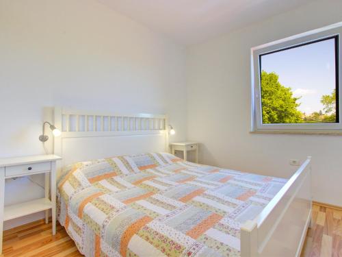 een witte slaapkamer met een bed en een raam bij Apartments Truške in Truške
