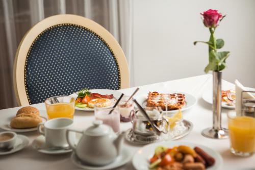 a table topped with plates of food and orange juice at Monika Centrum Hotels in Rīga
