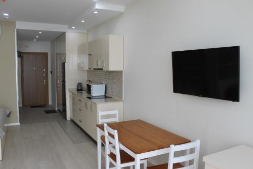 a kitchen with a table and a television on a wall at Batumi Porta Tower 1611 in Batumi