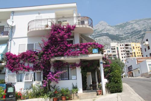 un edificio blanco con flores púrpuras. en Apartments Milena & Ante, en Makarska