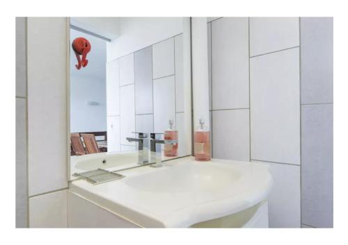 a white bathroom with a sink and a mirror at Appartement T2 Colombier pour 5 personnes vue mer in Sainte-Clotilde