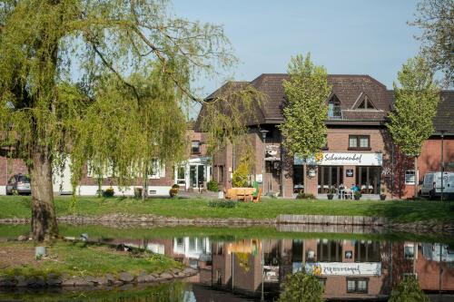 a building next to a river with a tree at Schwanenhof Hotel und Restaurant in Erkelenz