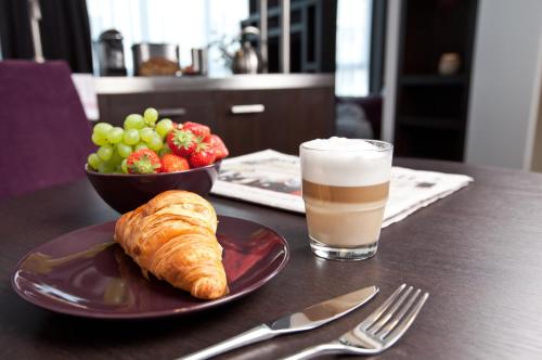 a table with a plate of croissant and a drink at Goodman's Living in Berlin