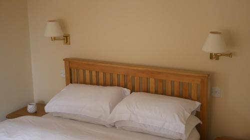 a bed with two white pillows and two lights on the wall at The Keep in Ludlow