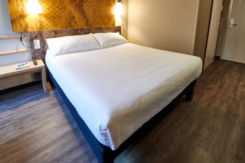a bed in a hotel room with a white bedspread at ibis Tilburg in Tilburg