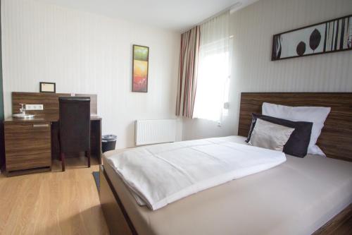 a bedroom with a large bed and a desk at Landhotel Wolfschlugen in Wolfschlugen