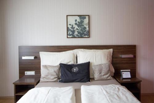 a bed with white pillows and a wooden headboard at Landhotel Wolfschlugen in Wolfschlugen