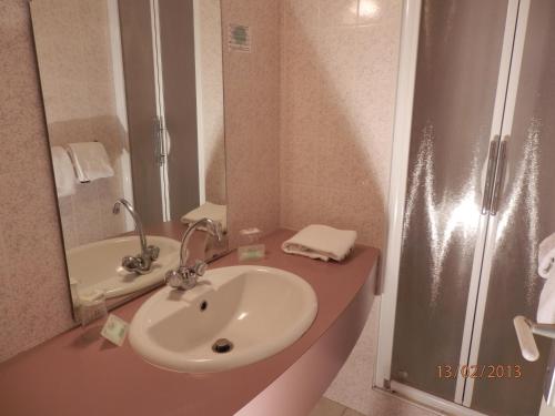 a bathroom with a sink and a shower at Hôtel de Paris in Lourdes