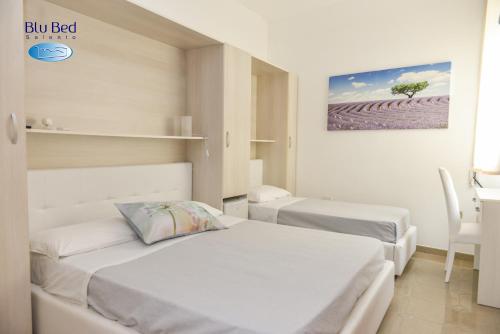 a bedroom with two beds and a table and a chair at Blu Bed Salento in Torre Lapillo