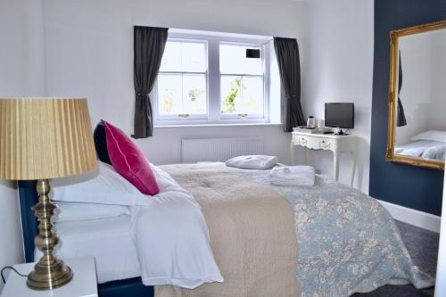a bedroom with a bed with pink pillows and a window at The Nags Head - Room only accommodation in Lyme Regis