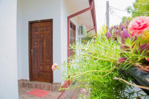 a wooden door in a white building with flowers at Aa Inn in Trincomalee