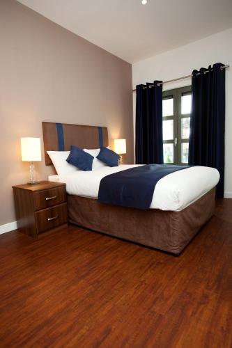 a bedroom with a large bed with blue pillows at The Spires Serviced Apartments Glasgow in Glasgow
