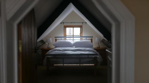 a bedroom with a bed in a attic with a window at The Keep in Ludlow