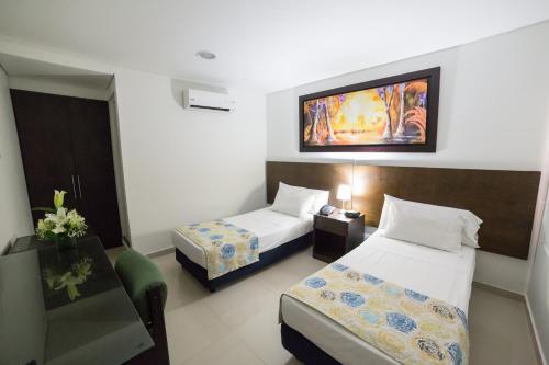 a small hotel room with two beds and a desk at San Martin Cartagena in Cartagena de Indias