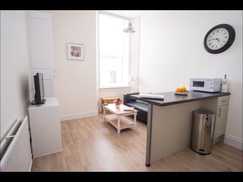 a kitchen with a desk and a clock on the wall at Cedar Apartment in Helensburgh