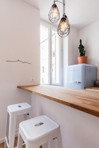 une cuisine avec deux tabourets blancs et deux lumières dans l'établissement 5 Sens, à Marseille