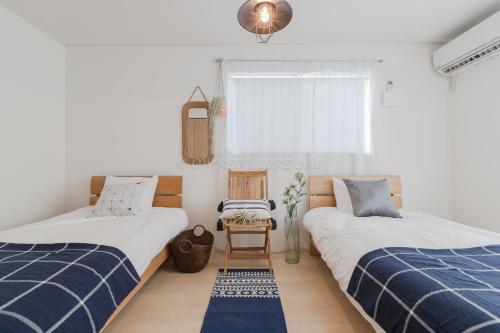 a bedroom with two beds and a chair at Condominium Palace Resort Chatan II in Chatan