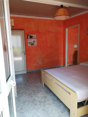 a bedroom with a bed and a orange wall at Villa Itaca in Sant'Isidoro