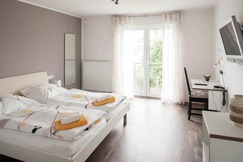 a white bedroom with two beds and a desk at Schwanenhof Hotel und Restaurant in Erkelenz