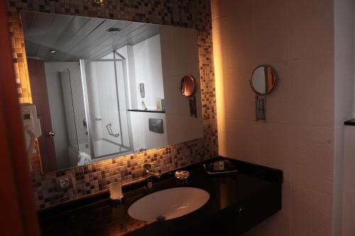 a bathroom with a sink and a large mirror at Akkoc Boutique Hotel in Adana