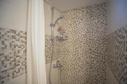 a shower in a bathroom with a tile wall at G & K City Apartments in Lefkada Town
